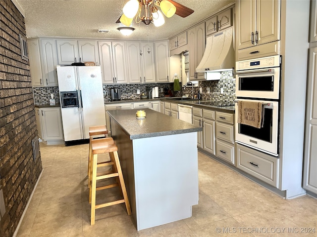 kitchen featuring a breakfast bar area, a center island, a textured ceiling, and white appliances