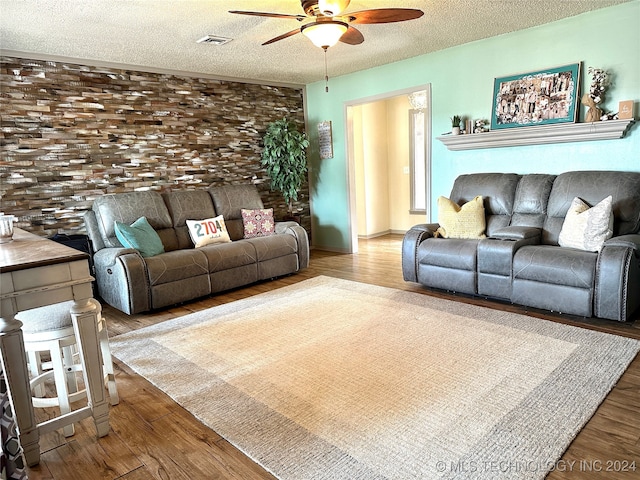 living room featuring ceiling fan, hardwood / wood-style flooring, and a textured ceiling