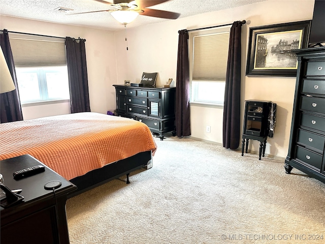 carpeted bedroom featuring ceiling fan, a textured ceiling, and multiple windows