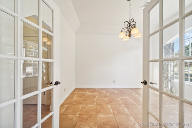 spare room with french doors and a notable chandelier