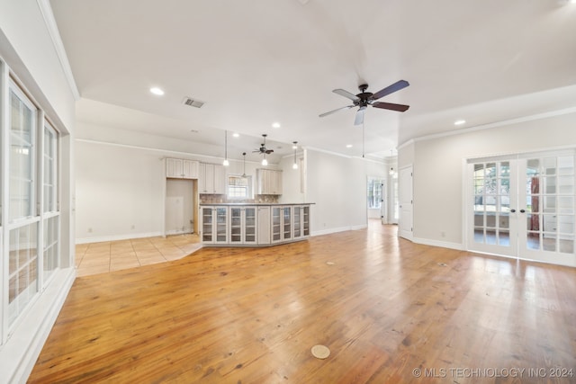 unfurnished living room featuring french doors, light hardwood / wood-style floors, crown molding, and ceiling fan