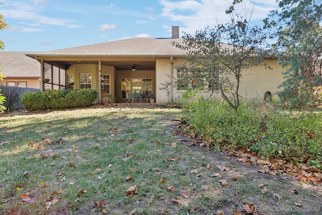 rear view of house featuring a yard and ceiling fan