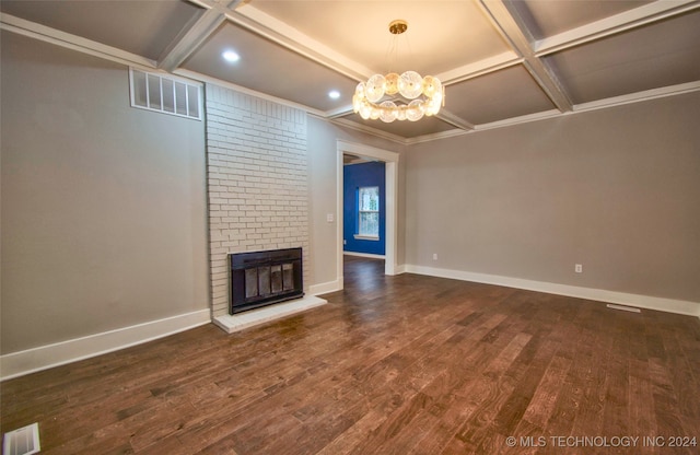 unfurnished living room with coffered ceiling, ornamental molding, an inviting chandelier, a fireplace, and dark hardwood / wood-style flooring