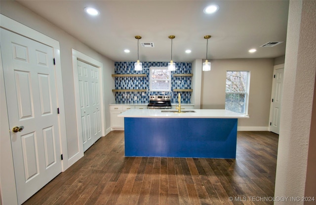 kitchen with dark wood-type flooring, decorative light fixtures, stainless steel stove, and sink