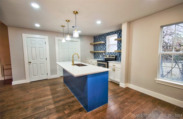 kitchen featuring stainless steel range with electric cooktop, a kitchen island with sink, dark hardwood / wood-style floors, pendant lighting, and sink