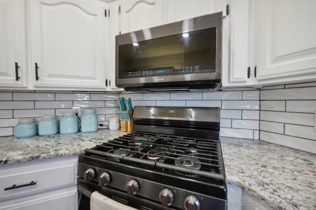 kitchen with tasteful backsplash, white cabinetry, appliances with stainless steel finishes, sink, and dark wood-type flooring