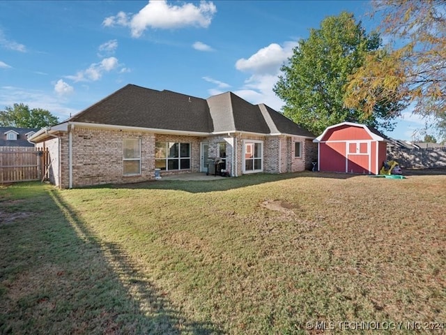 rear view of house featuring a patio, a lawn, and a storage unit