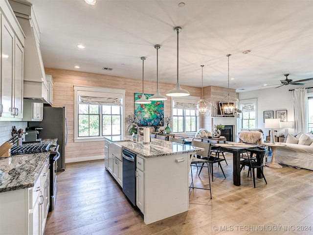 kitchen with white cabinets, hanging light fixtures, and a center island with sink