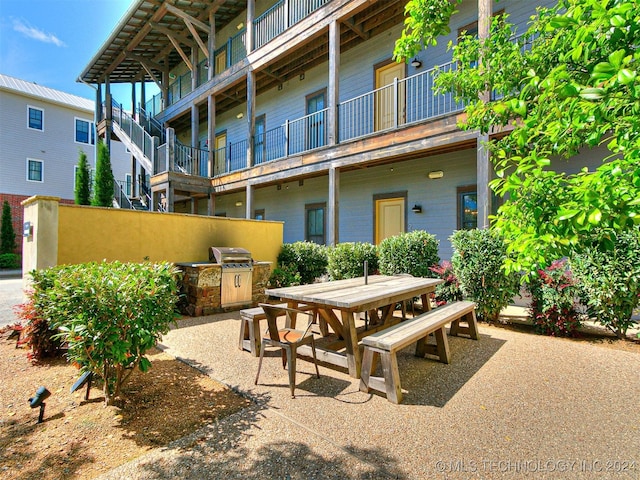 view of patio featuring a grill, a balcony, and exterior kitchen