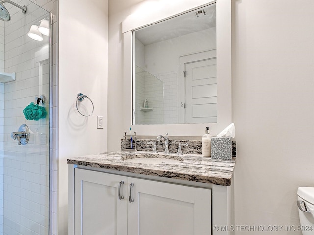 bathroom featuring toilet, a shower with shower door, and vanity