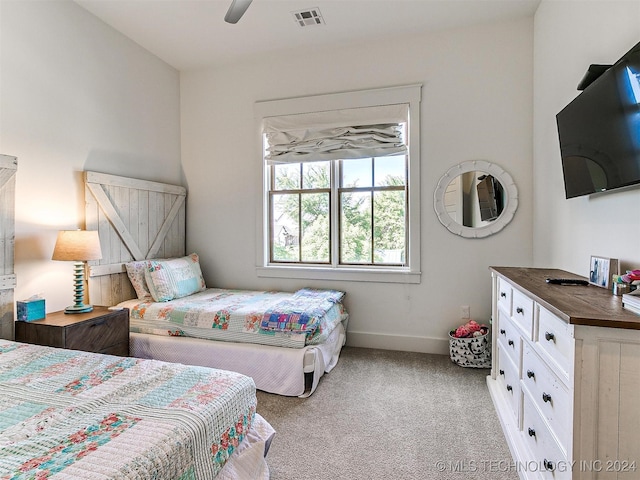 carpeted bedroom with a barn door and ceiling fan