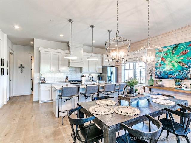 dining room with light hardwood / wood-style flooring and an inviting chandelier