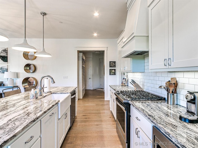 kitchen with light hardwood / wood-style flooring, hanging light fixtures, stainless steel appliances, light stone countertops, and white cabinetry