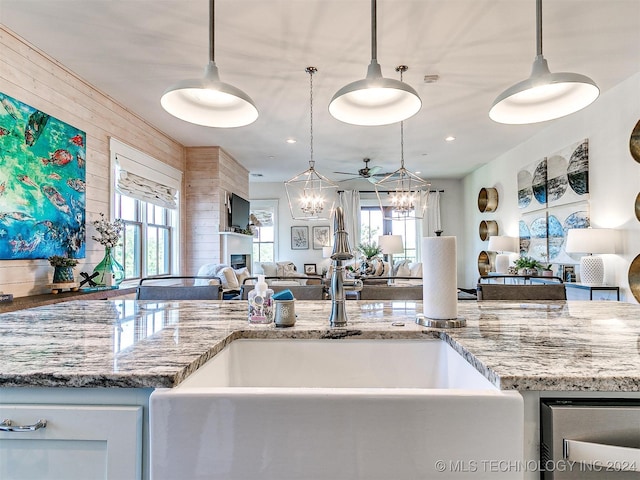 kitchen featuring wooden walls, white cabinetry, hanging light fixtures, and ceiling fan