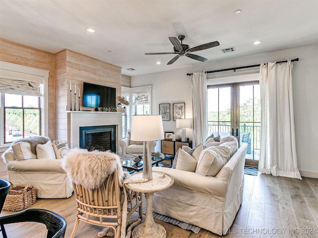 living room featuring a large fireplace, hardwood / wood-style flooring, plenty of natural light, and wood walls