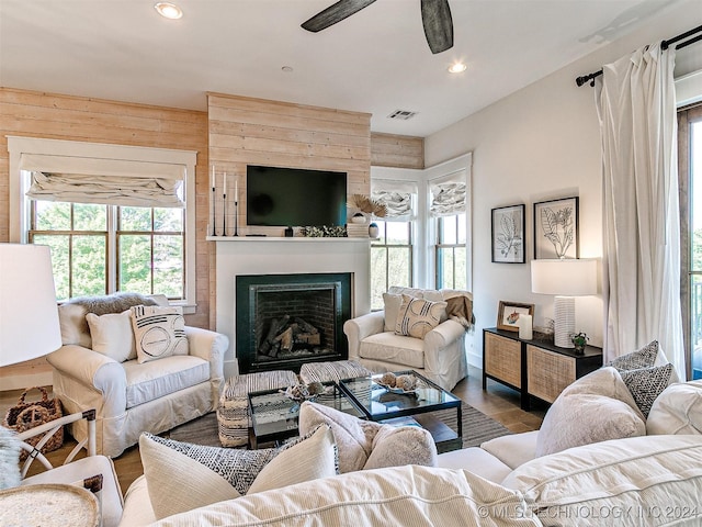 living room featuring hardwood / wood-style floors, a fireplace, wooden walls, and ceiling fan