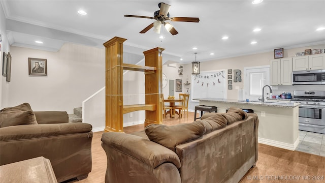 living room with ornamental molding, sink, light hardwood / wood-style floors, and ceiling fan