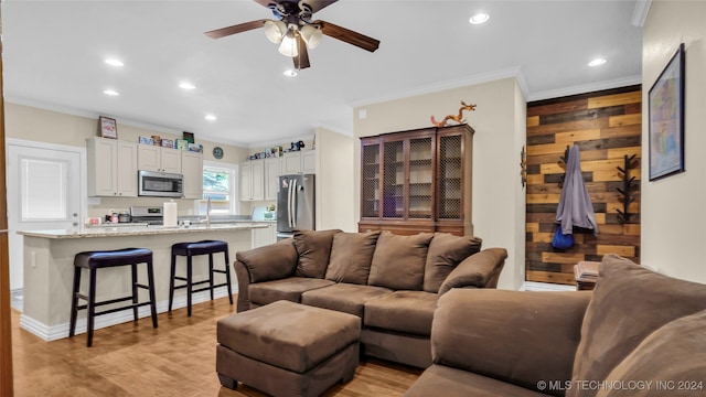 living room featuring light hardwood / wood-style floors, ornamental molding, and ceiling fan