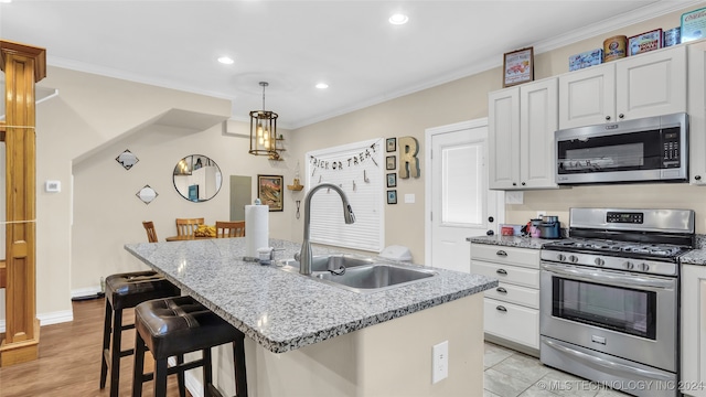 kitchen featuring white cabinetry, stainless steel appliances, sink, and an island with sink