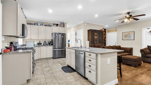 kitchen featuring an island with sink, stainless steel appliances, ornamental molding, sink, and white cabinets