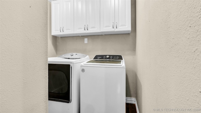 laundry area with washing machine and clothes dryer and cabinets