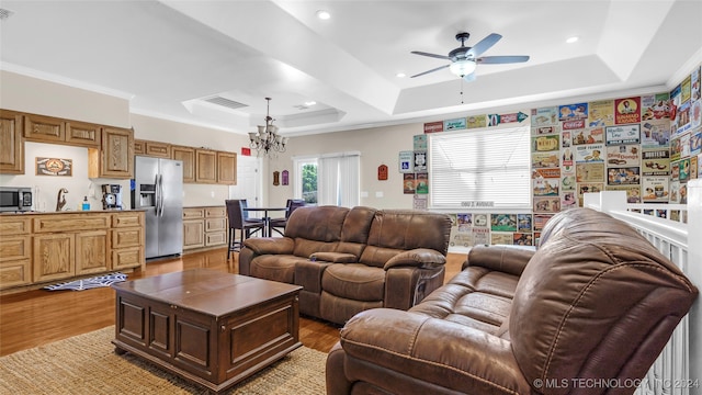 living room featuring a tray ceiling, ornamental molding, and light hardwood / wood-style flooring