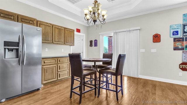 dining room featuring a chandelier, crown molding, a tray ceiling, and light wood-type flooring