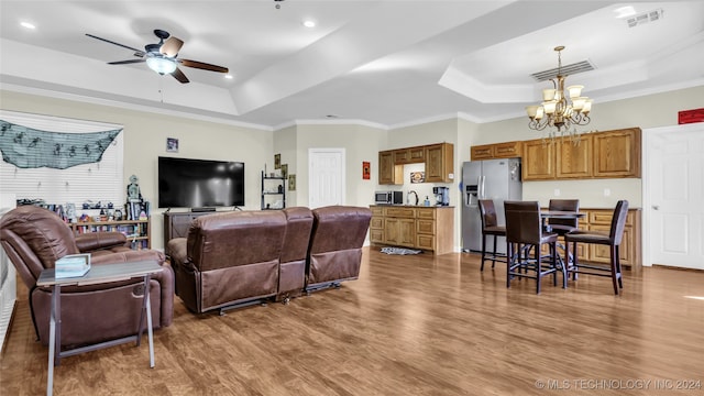 living room featuring ornamental molding, wood-type flooring, and a raised ceiling