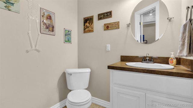 bathroom with toilet, vanity, and tile patterned flooring