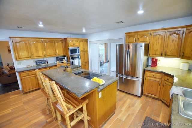 kitchen featuring decorative backsplash, stainless steel appliances, a breakfast bar, a center island, and light hardwood / wood-style floors