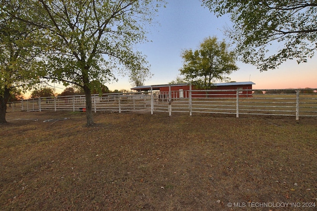 yard at dusk featuring a rural view