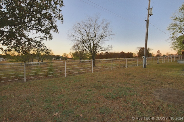 yard at dusk featuring a rural view