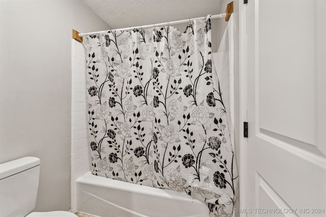 bathroom with shower / bath combo with shower curtain, a textured ceiling, and toilet