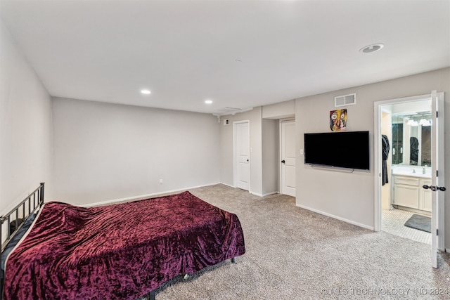 bedroom featuring ensuite bathroom and light colored carpet