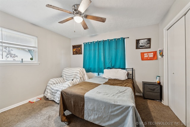 bedroom with carpet flooring, ceiling fan, a closet, and a textured ceiling