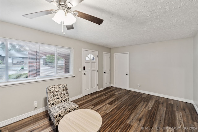 living area with a textured ceiling, ceiling fan, and dark hardwood / wood-style floors