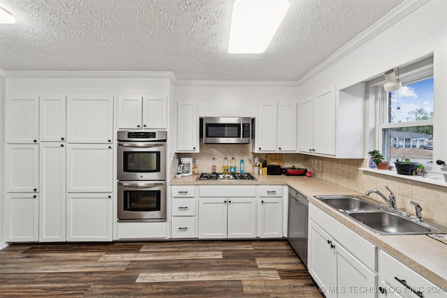 kitchen with sink, stainless steel appliances, a textured ceiling, decorative backsplash, and white cabinets