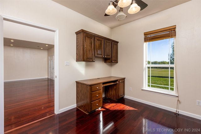unfurnished office with dark wood-type flooring, baseboards, healthy amount of natural light, and a chandelier