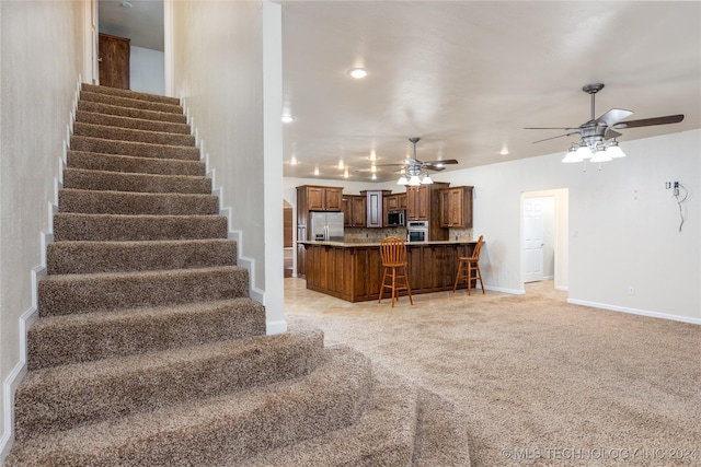 stairway featuring ceiling fan and baseboards