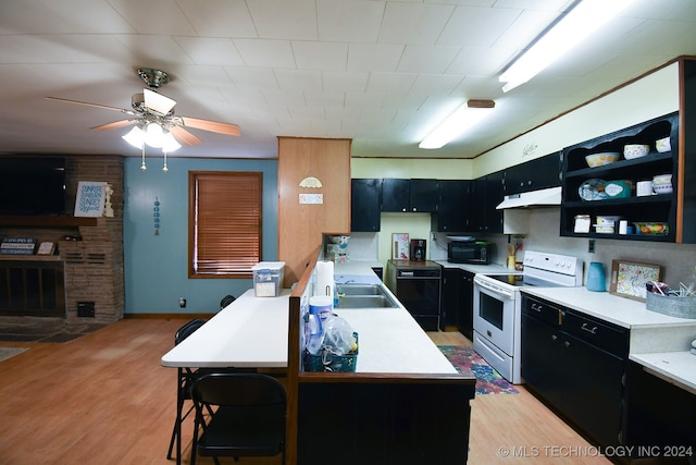 kitchen with black appliances, a kitchen breakfast bar, sink, and light hardwood / wood-style floors