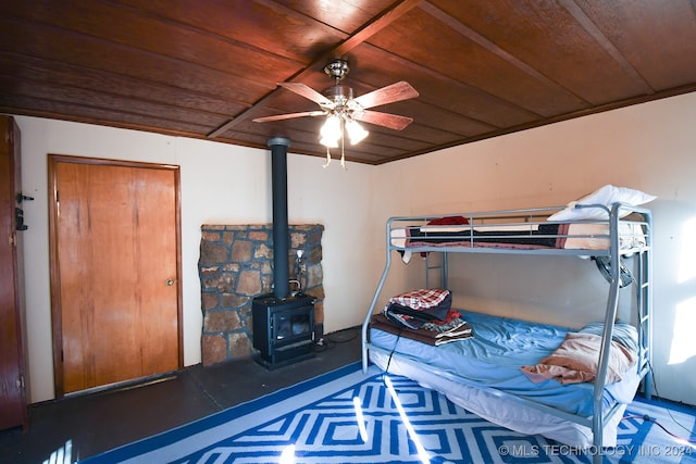 bedroom with a wood stove, ceiling fan, and wooden ceiling