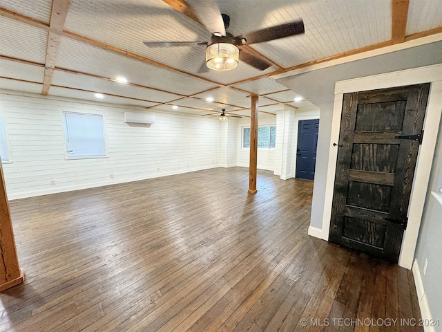 interior space with dark hardwood / wood-style flooring, wood walls, and ceiling fan