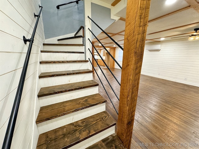 stairway with hardwood / wood-style flooring and wooden walls