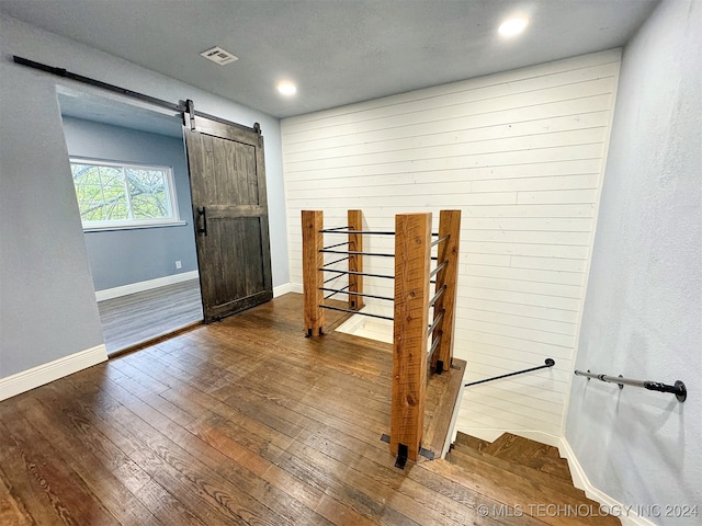 foyer with hardwood / wood-style floors, wood walls, and a barn door