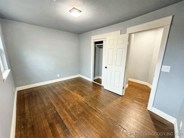 unfurnished bedroom featuring hardwood / wood-style floors, a textured ceiling, and a closet