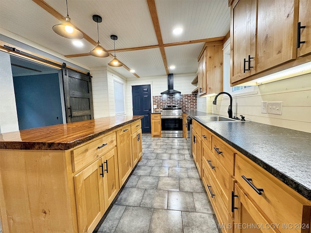 kitchen with wall chimney exhaust hood, stainless steel range oven, a barn door, sink, and pendant lighting