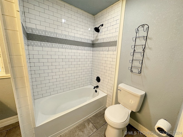 bathroom with tile patterned floors, tiled shower / bath combo, and toilet