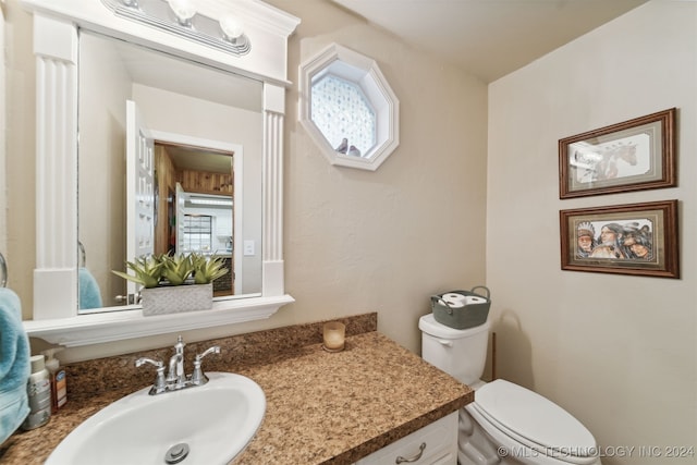 bathroom featuring a wealth of natural light, vanity, and toilet