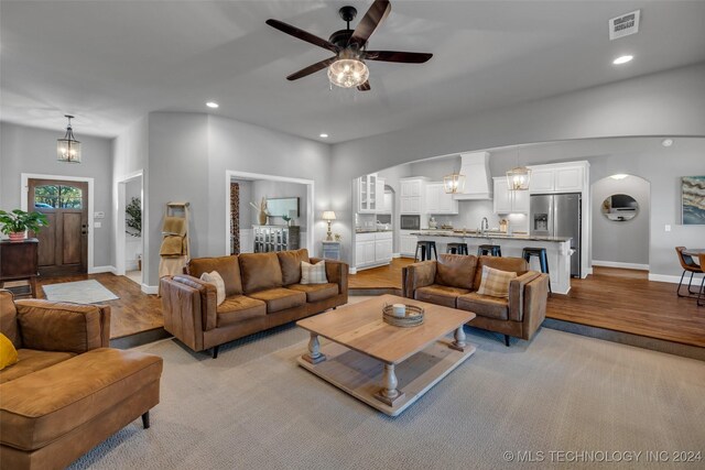 living area featuring arched walkways, a ceiling fan, baseboards, recessed lighting, and light carpet
