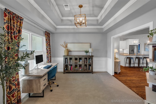 office area featuring ornamental molding, a raised ceiling, carpet floors, and a chandelier